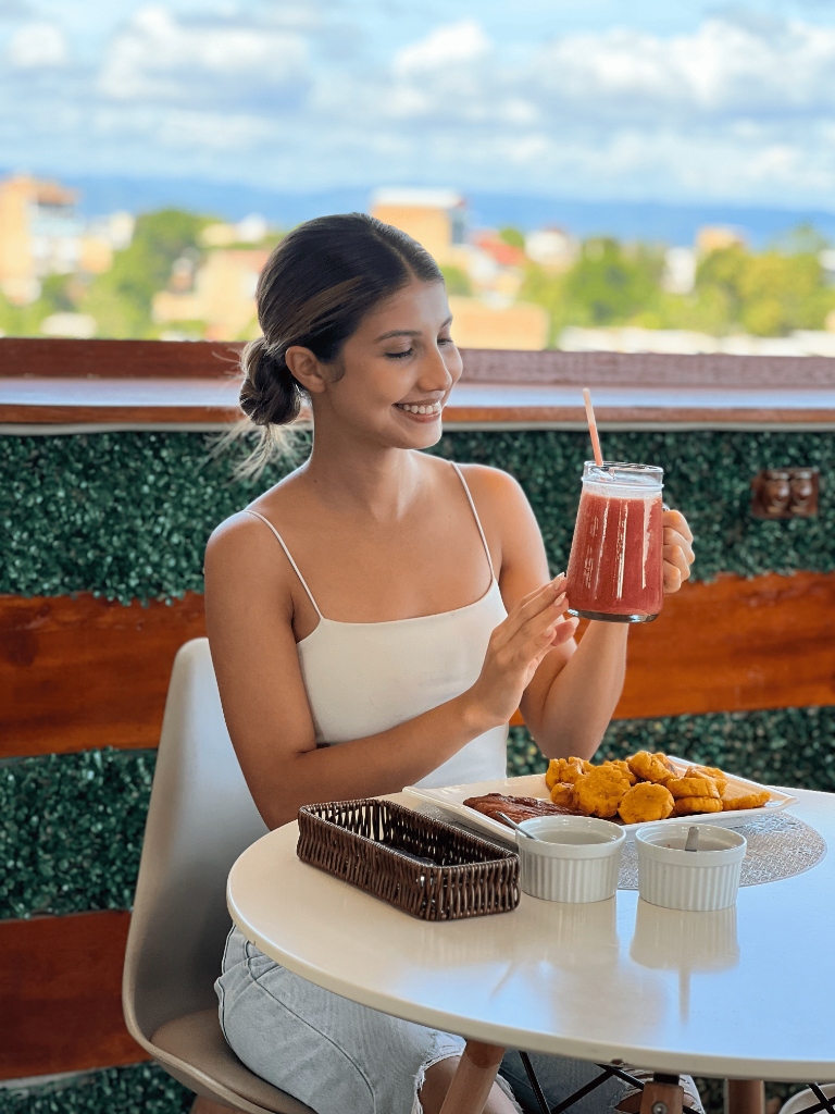 Huésped disfrutando de jugos y comida en la terraza con vista